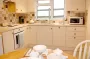 A wide view of the kitchen, showing appliances, a sink and the window.