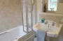 A white bathroom with bath, shower, sink and blue towel.